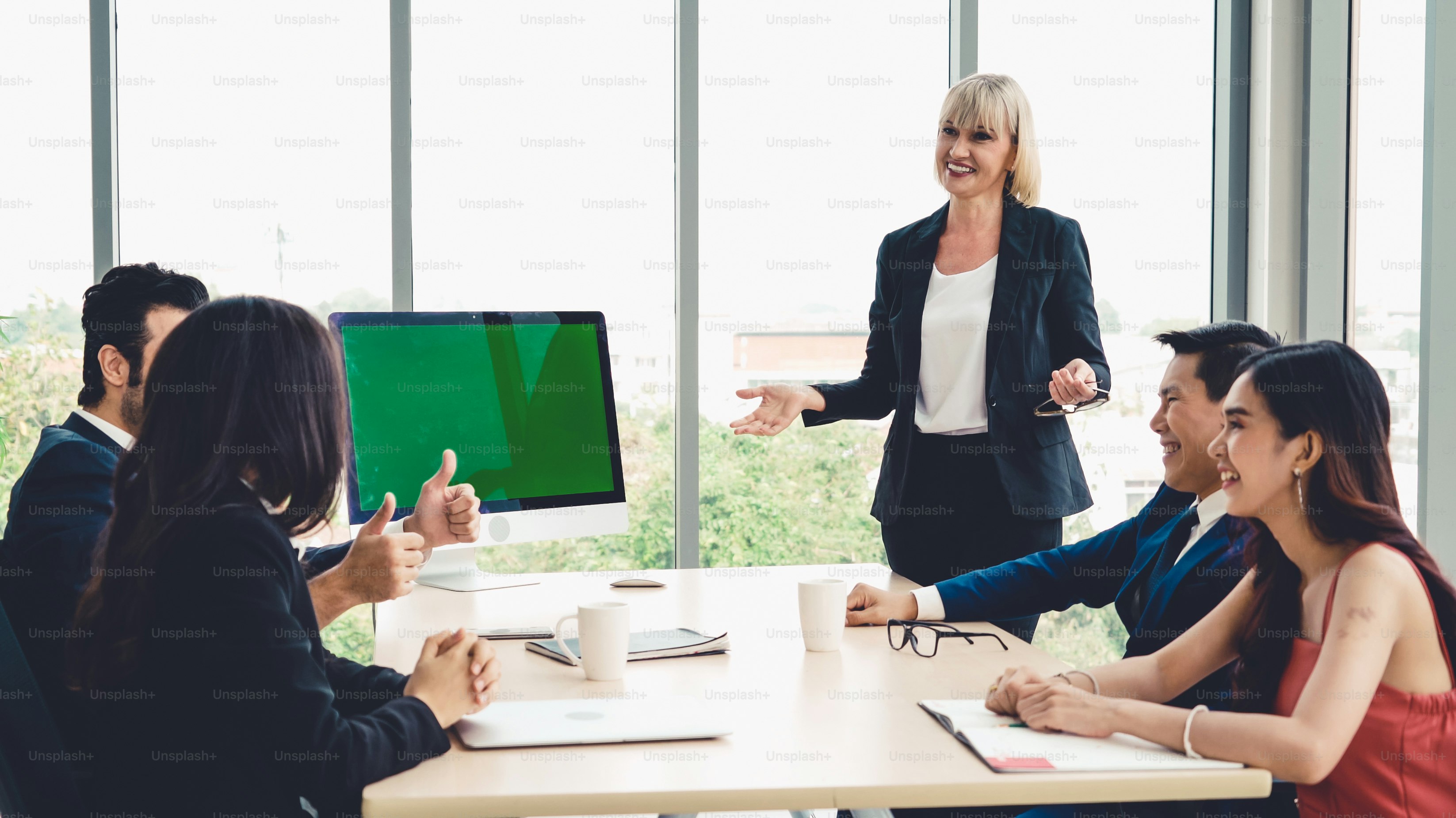 Business people in the conference room with green screen chroma key TV or computer on the office table. Diverse group of businessman and businesswoman in meeting on video conference call .