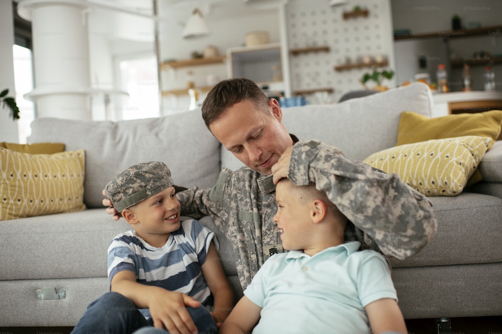 Happy soldier sitting on the floor with his family. Soldier enjoying at home with children.