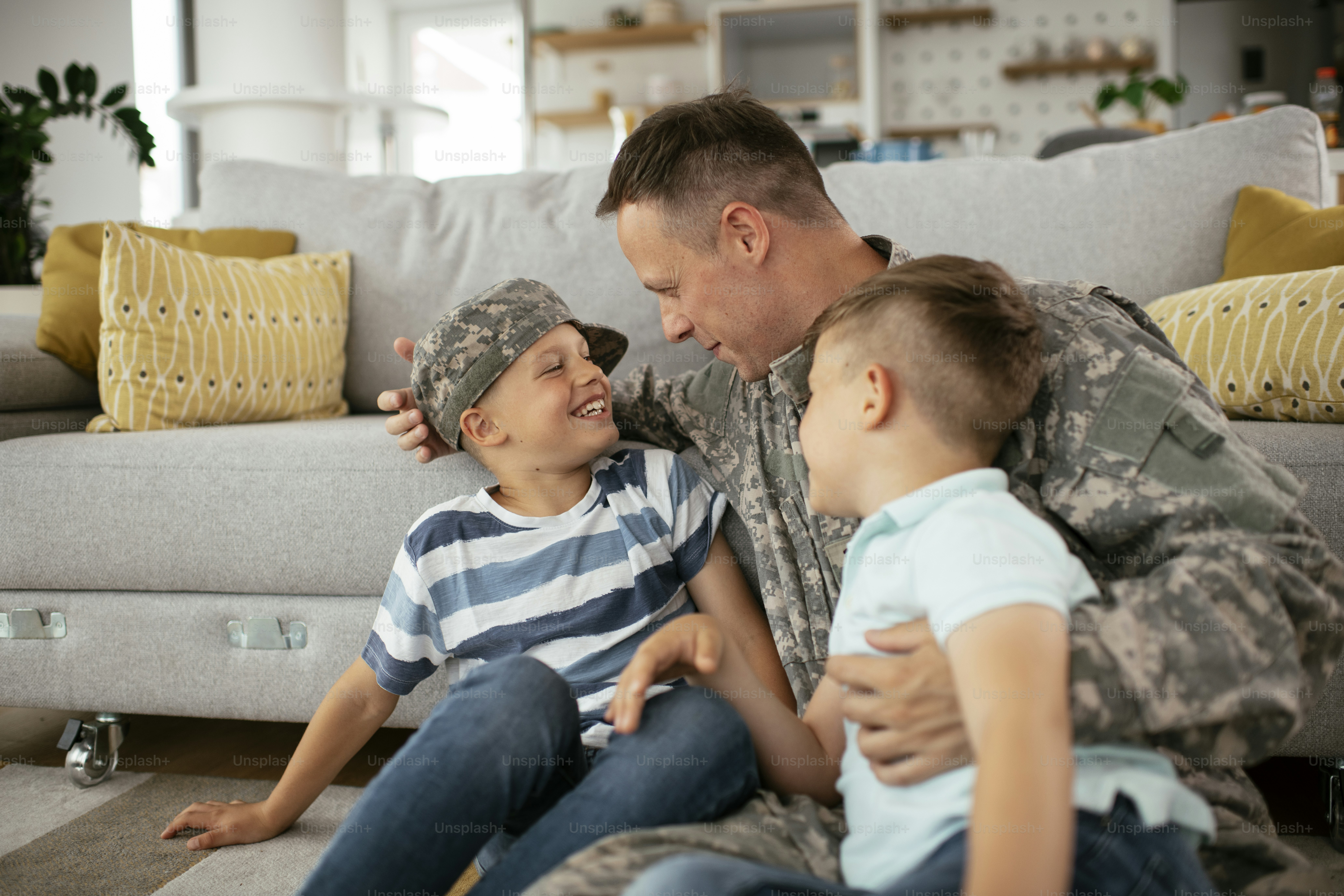 Happy soldier sitting on the floor with his family. Soldier enjoying at ...