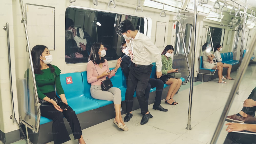 La donna impedisce all'uomo di sedersi accanto a lei sul treno per il distanziamento sociale. Malattia da coronavirus o epidemia di pandemia COVID 19 e problema di stile di vita urbano nel concetto di ora di punta.