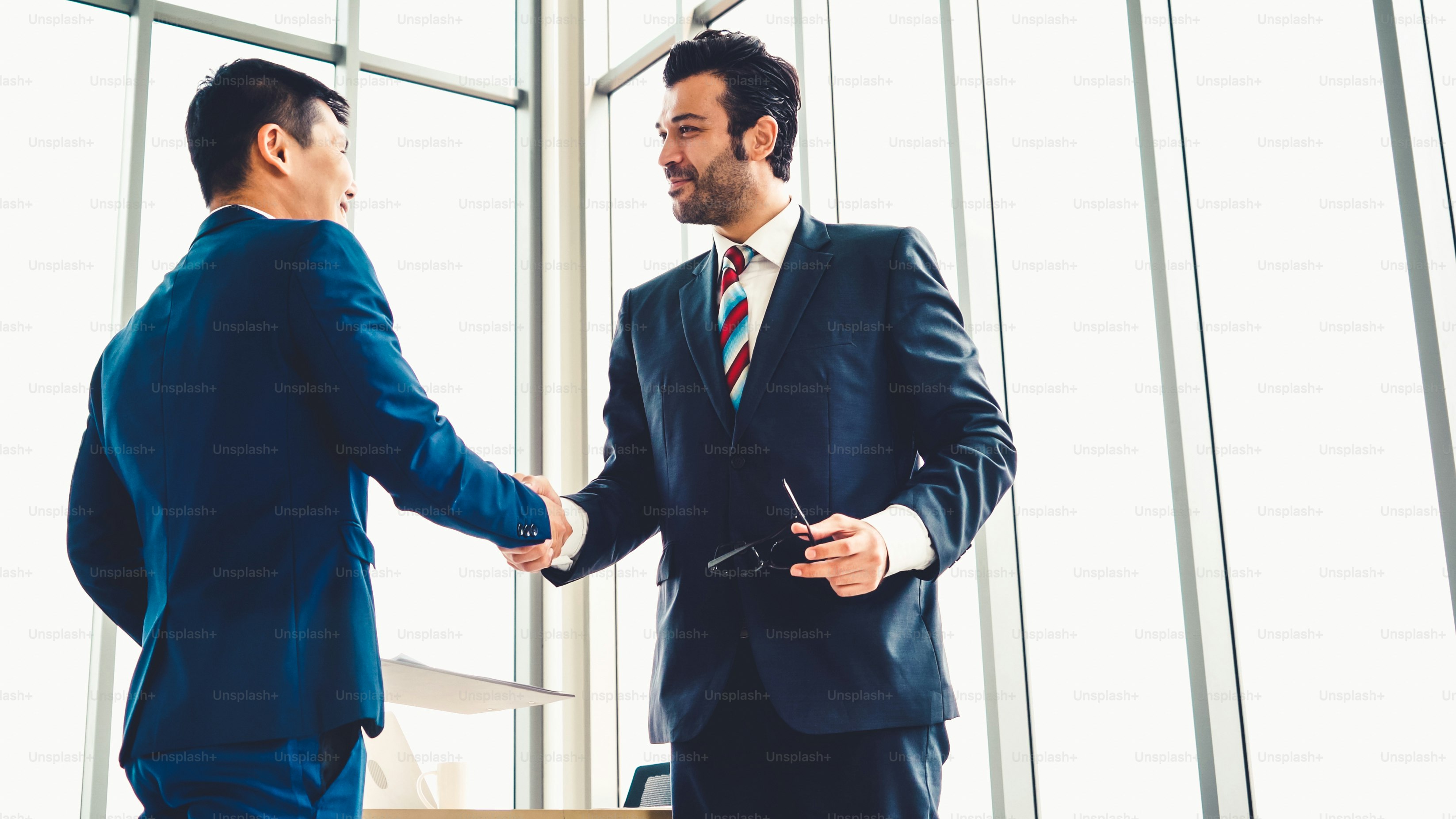 Business people handshake in corporate office showing professional agreement on a financial deal contract.