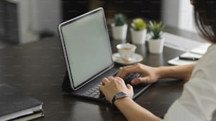 Foto recortada de una joven oficinista escribiendo en una computadora portátil en una oficina moderna