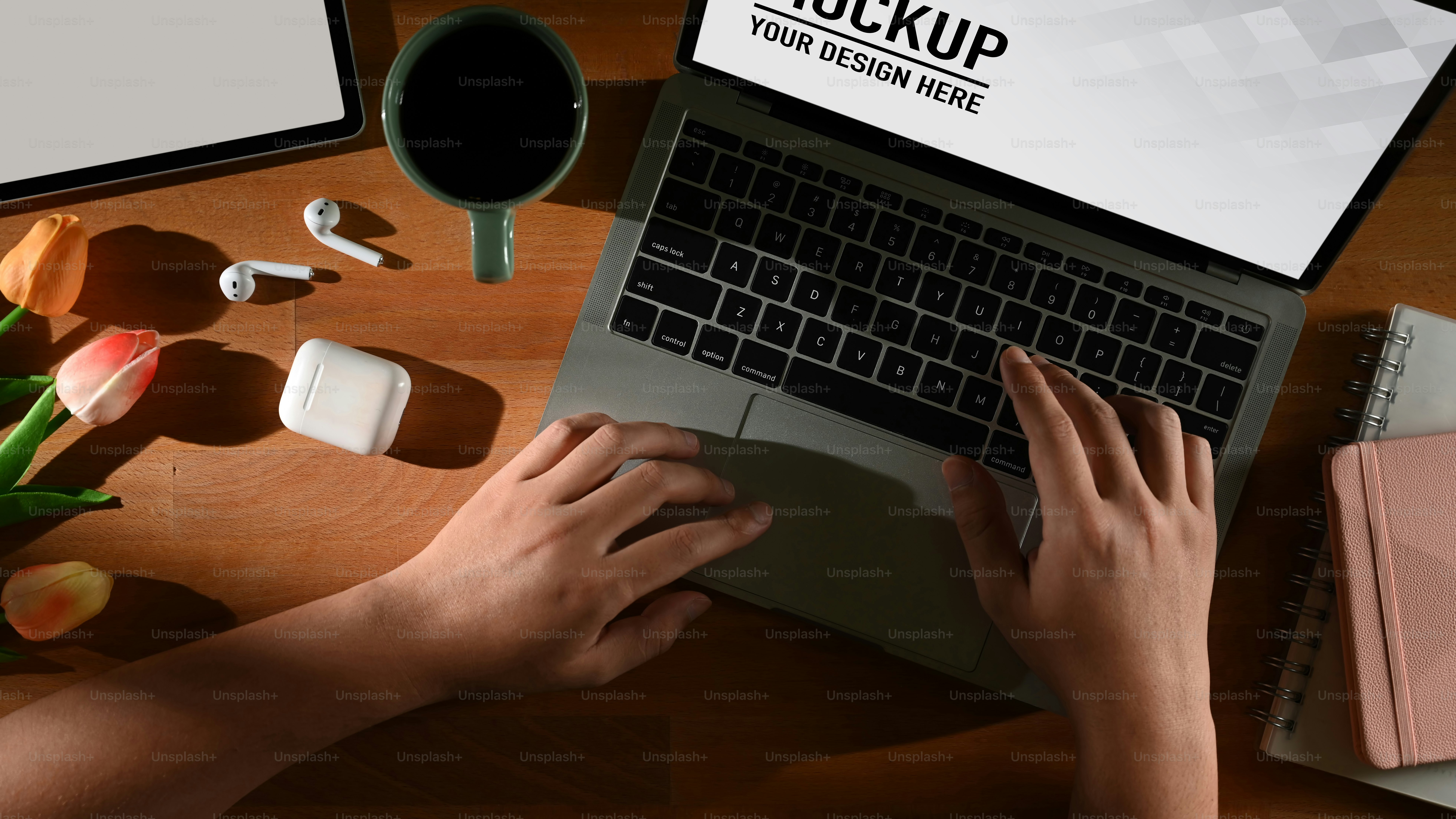 Top view of male hands typing on laptop on wooden table with supplies and flower, include clipping path
