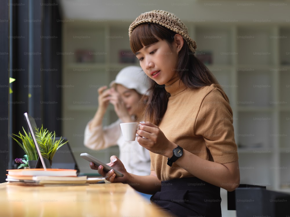 Portrait of female teenager using smartphone and take a coffee break while doing homework in cafe