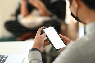 Cropped shot of man hands holding mock up smartphone blank screen while sitting in meeting room.