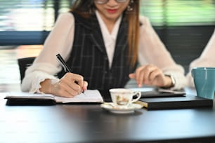 Una oficinista que trabaja con una tableta de computadora y escribe en un cuaderno en una oficina moderna.