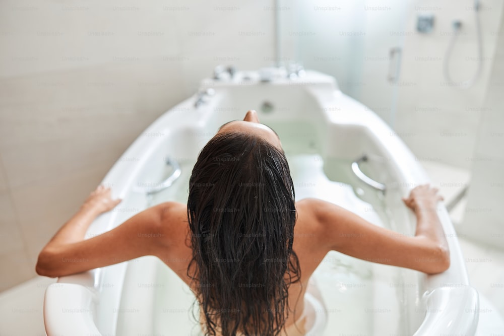 Top view of lady with long wet hair taking bath at home