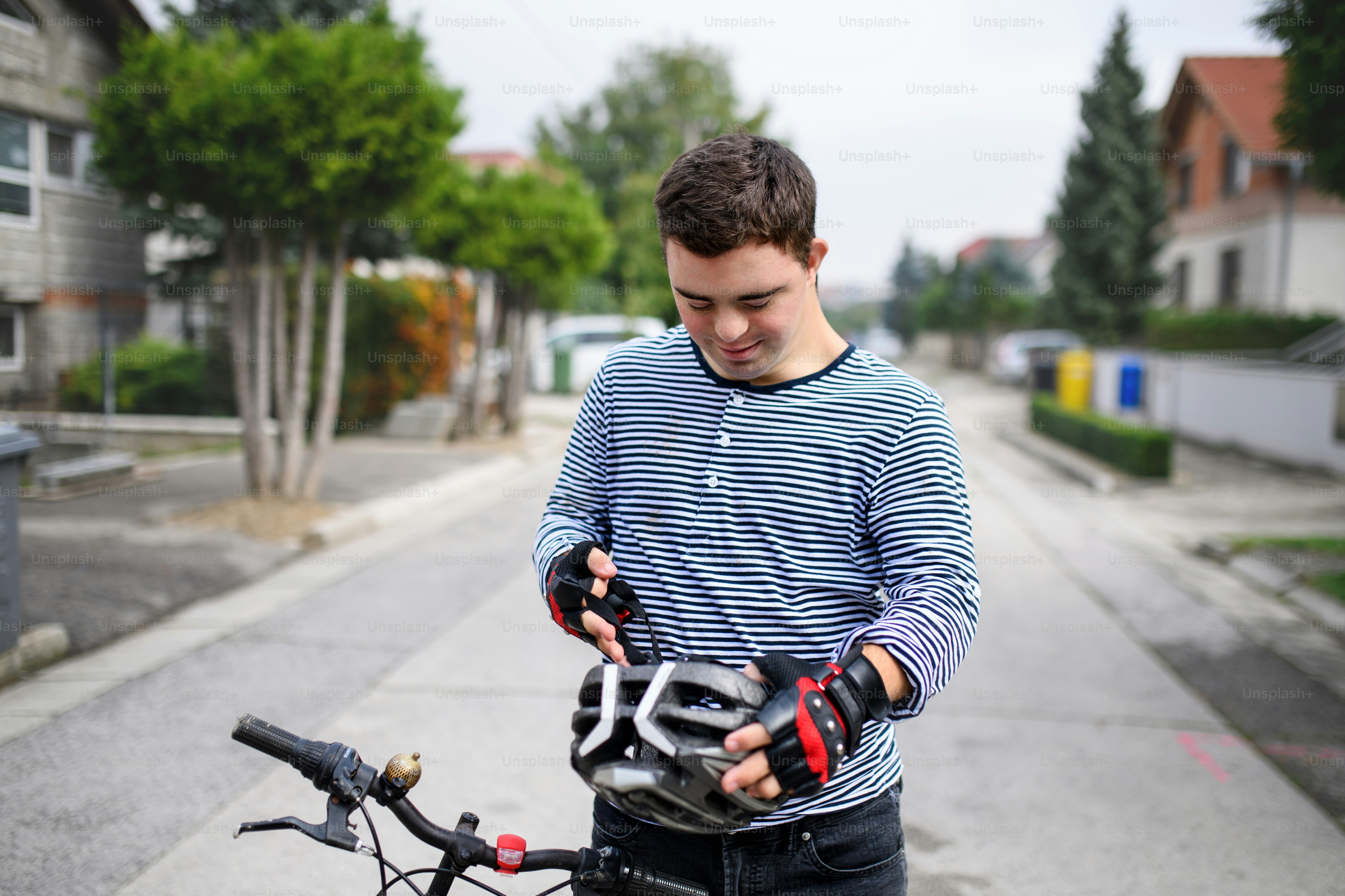 Portrait of down syndrome adult man with bicycle and helmet standing