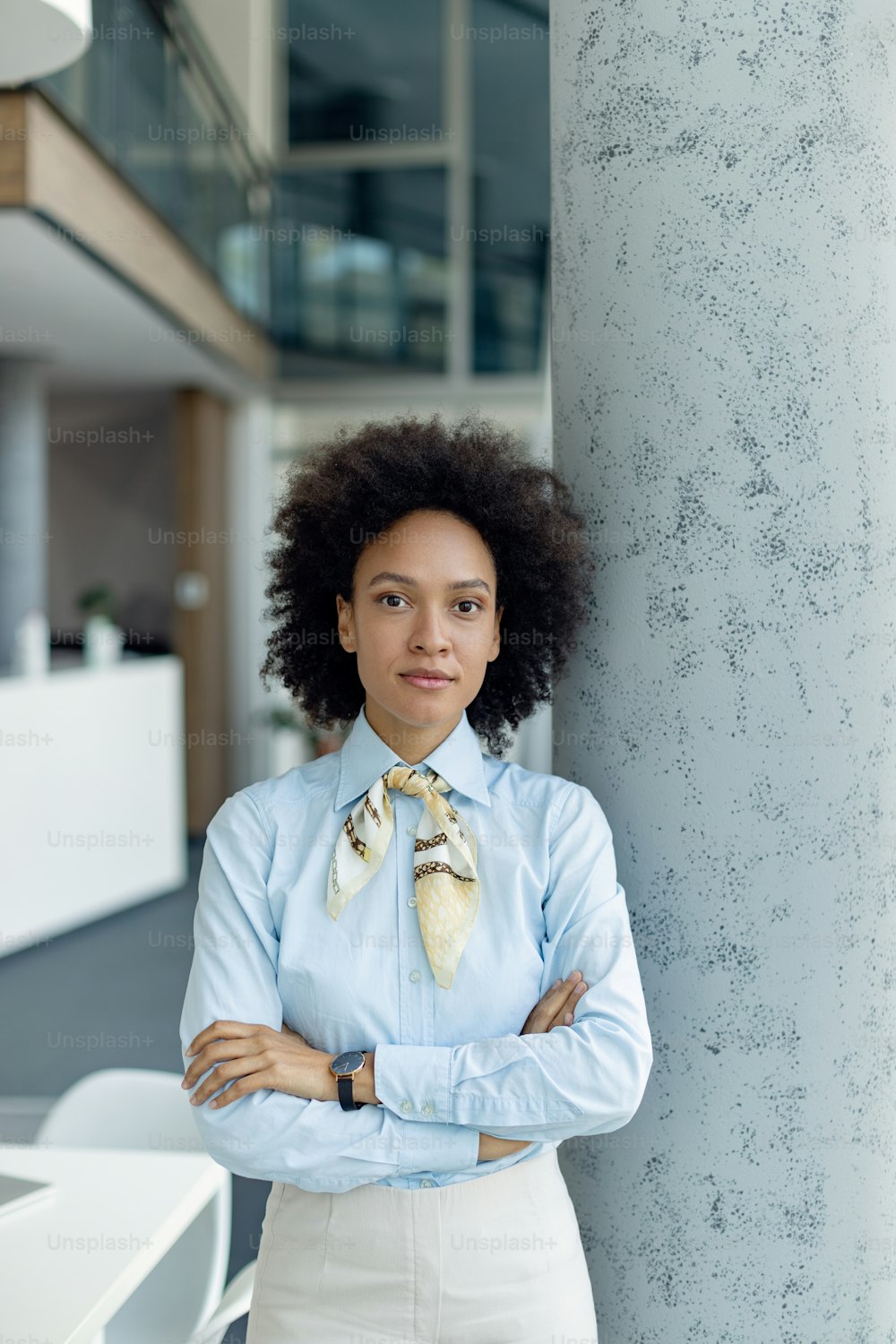 Confident African American businesswoman standing with arms crossed in the office while looking at camera. Copy space.
