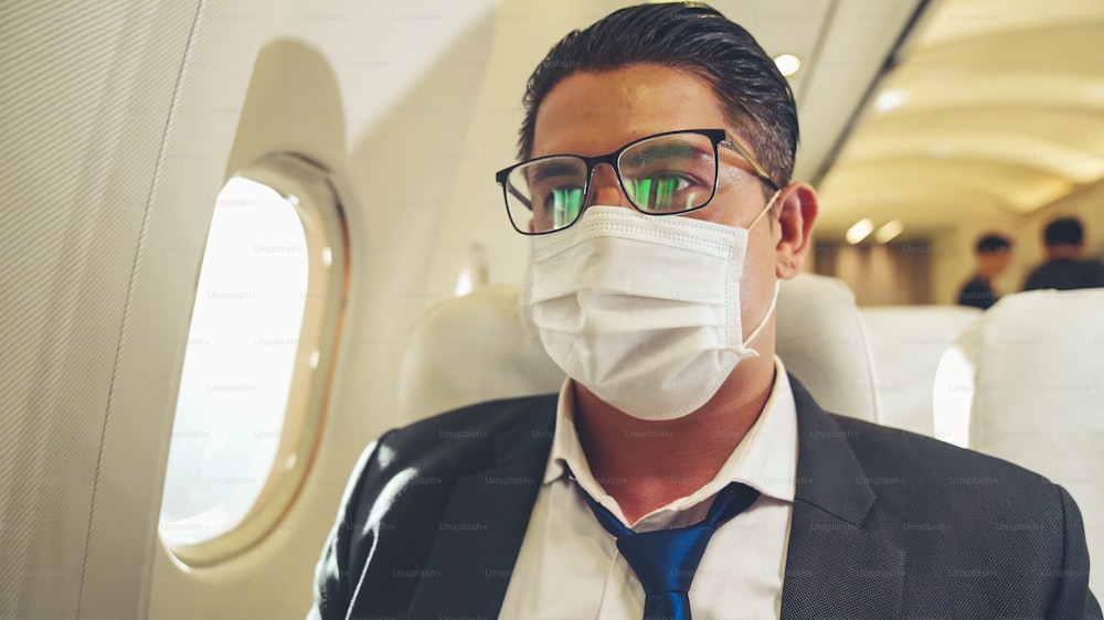 Viajante usando máscara facial durante a viagem em avião comercial. Conceito de doença por coronavírus ou efeitos do surto da pandemia de COVID 19 no turismo e nos negócios aéreos.