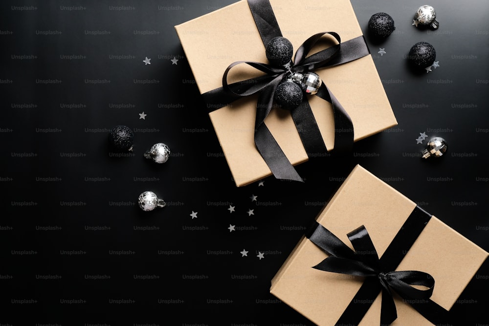 Elegant Christmas present boxes and balls on black background. Flat lay, top view. Christmas surprise, New Year gift box concept.