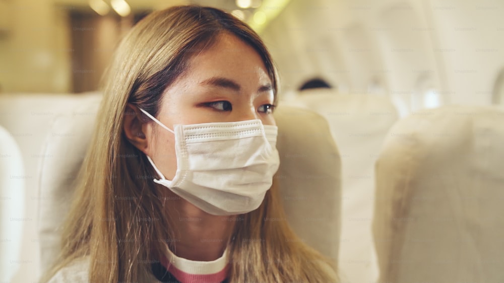民間航空機での旅行中にフェイスマスクを着用する旅行者。コロナウイルス病またはCOVID19パンデミックの発生が観光および航空事業に及ぼす影響の概念。