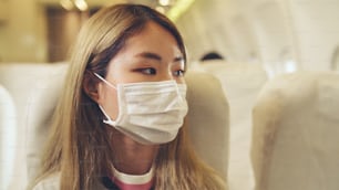 Reisender, der eine Gesichtsmaske trägt, während er in einem Verkehrsflugzeug reist. Konzept der Coronavirus-Krankheit oder COVID-19-Pandemie-Ausbruch Auswirkungen auf Tourismus und Fluggeschäft.