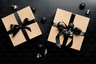 Luxury gift boxes decorated black ribbon bows and balls on black background. Christmas present, New Year gift box concept.