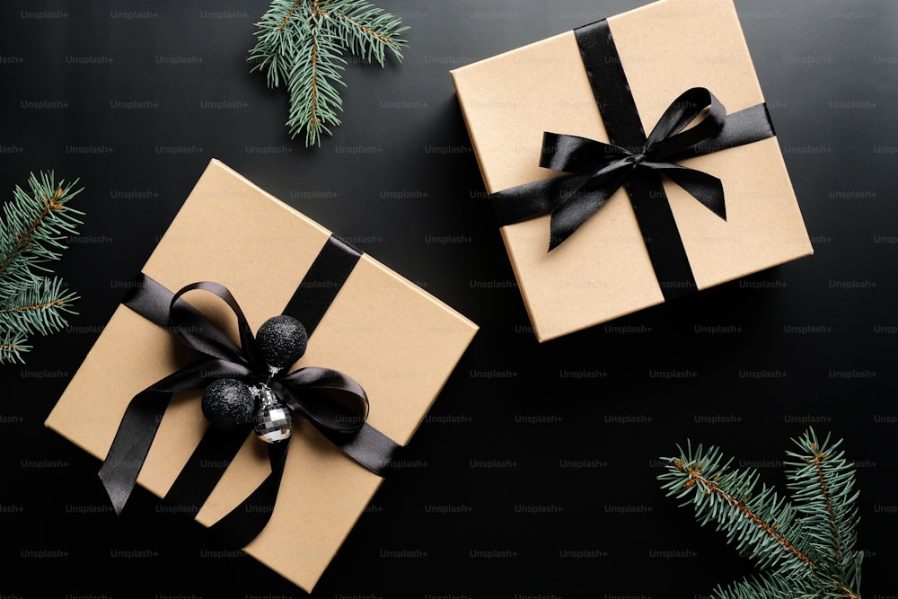 Cajas de regalo de Navidad de lujo y ramas de abeto sobre fondo negro. Plano, vista superior. Regalo de Navidad, concepto sorpresa de Año Nuevo.