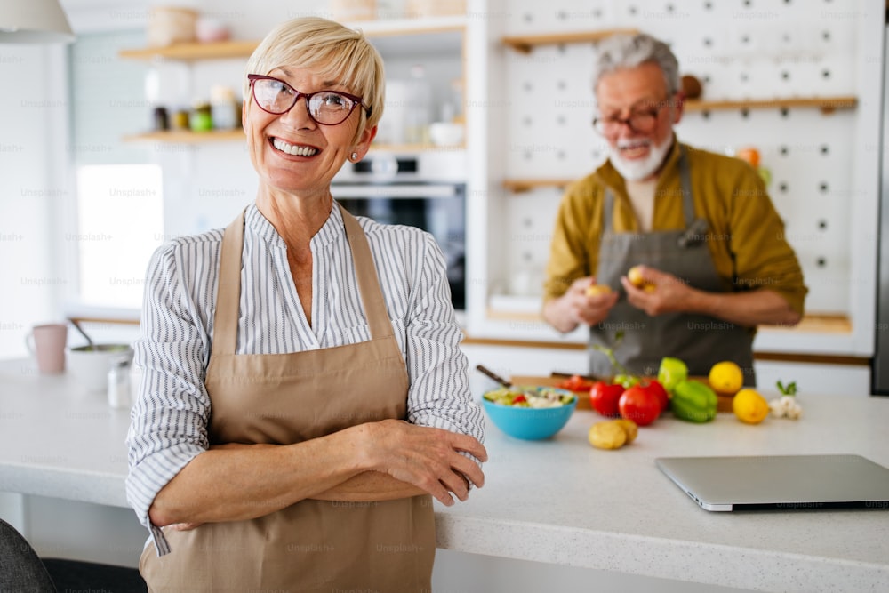 Happy senior couple having fun in kitchen with healthy food at home