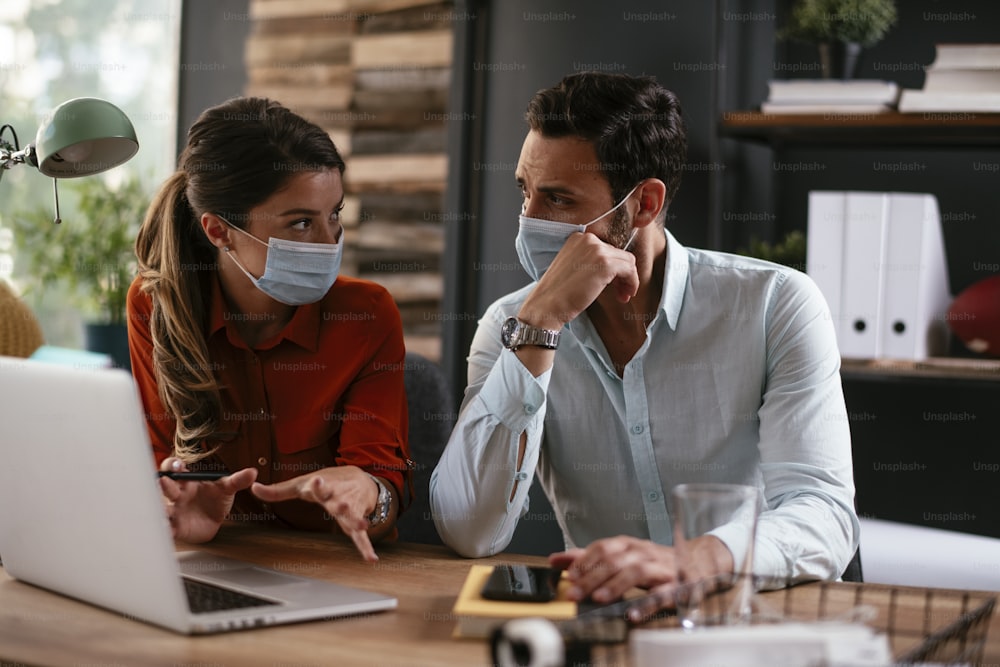 Businessman and businesswoman with medical mask in office. Colleagues working in office