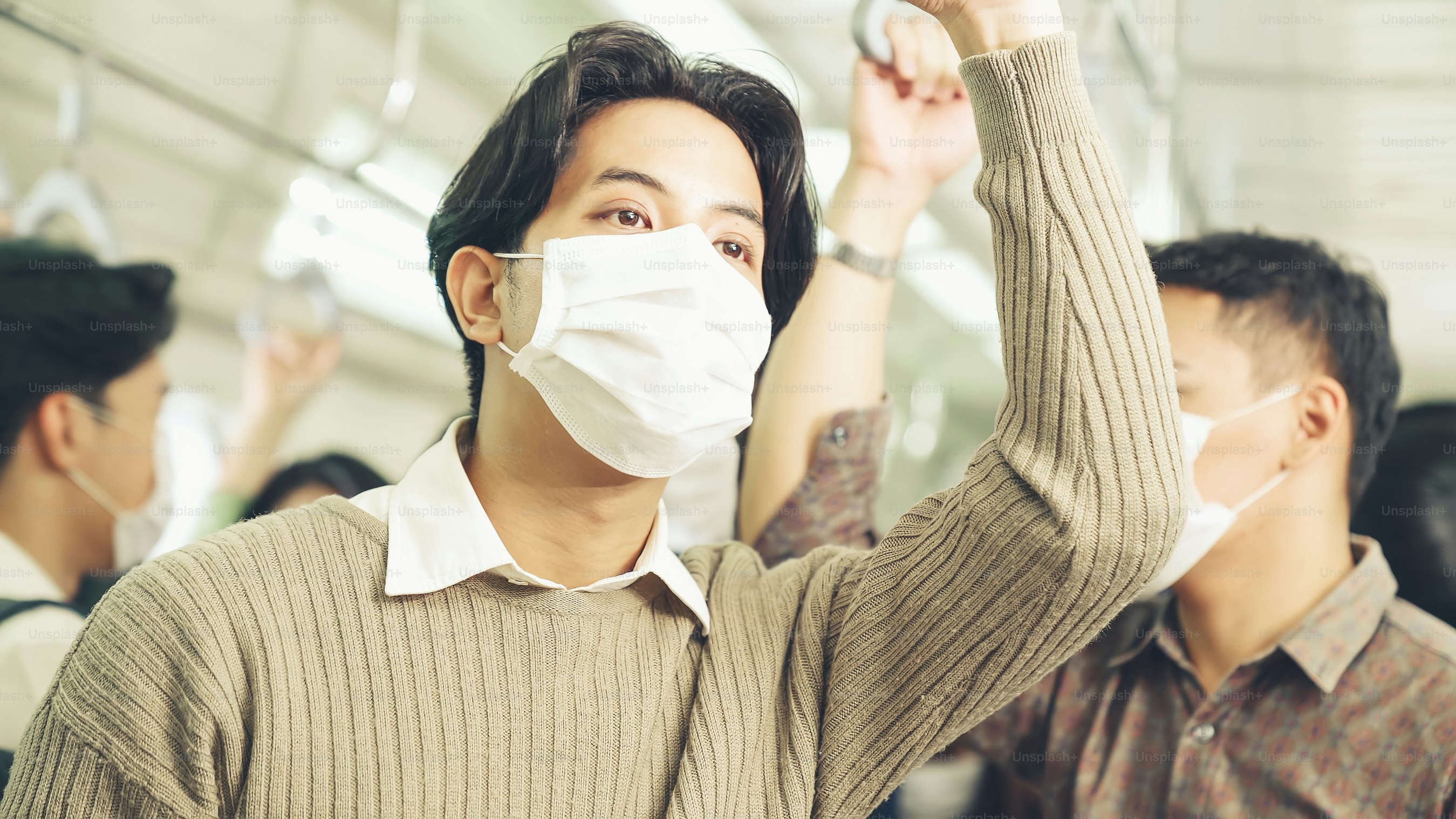 Young man wearing face mask travels on crowded subway train . Coronavirus disease or COVID 19 pandemic outbreak and urban lifestyle problem in rush hour concept .