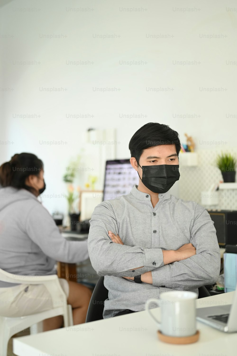 Zwei Büroangestellte arbeiten und tragen eine Maske zum Schutz vor Covid19 oder der Coronavirus-Krankheit.