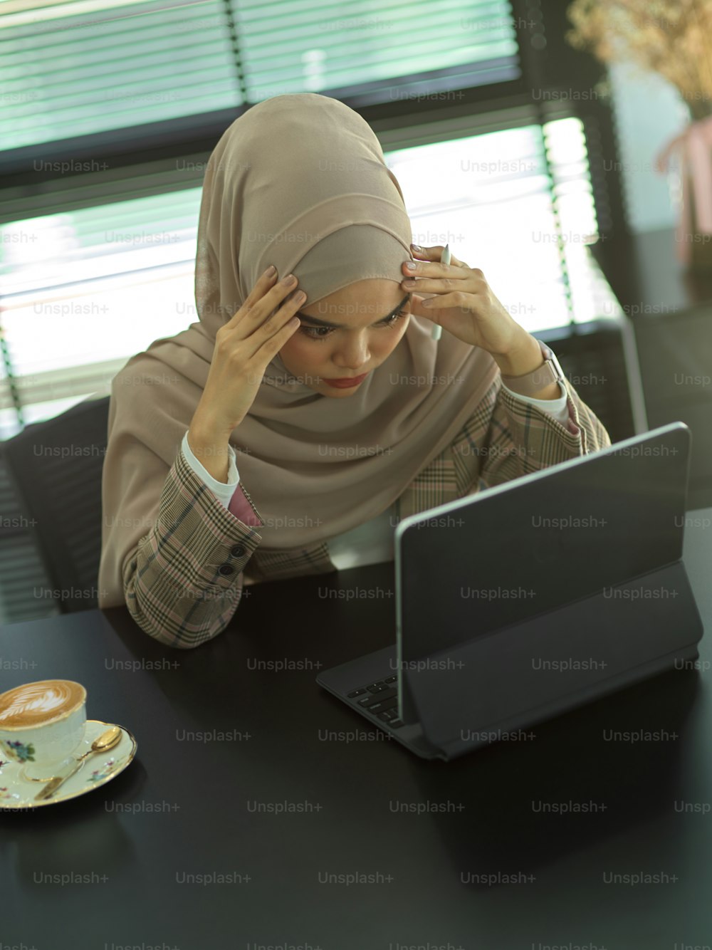 Draufsicht auf junge muslimische Geschäftsfrau, die sich bei der Arbeit im Büroraum gestresst fühlt
