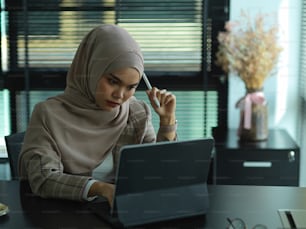 Porträt einer jungen muslimischen Geschäftsfrau, die sich bei der Arbeit im Büroraum gestresst fühlt