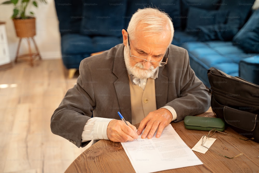 Elegant caucasian senior man signing documents of health insurance.