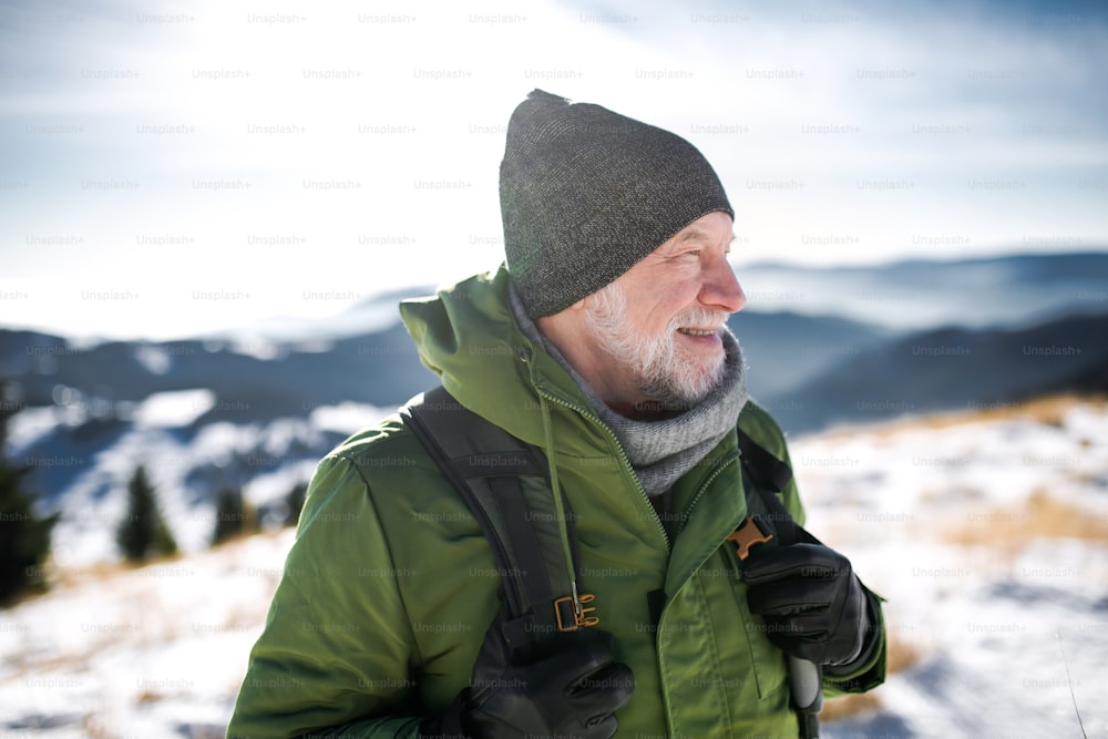 Retrato de vista frontal de un hombre mayor de pie en la naturaleza invernal cubierta de nieve.