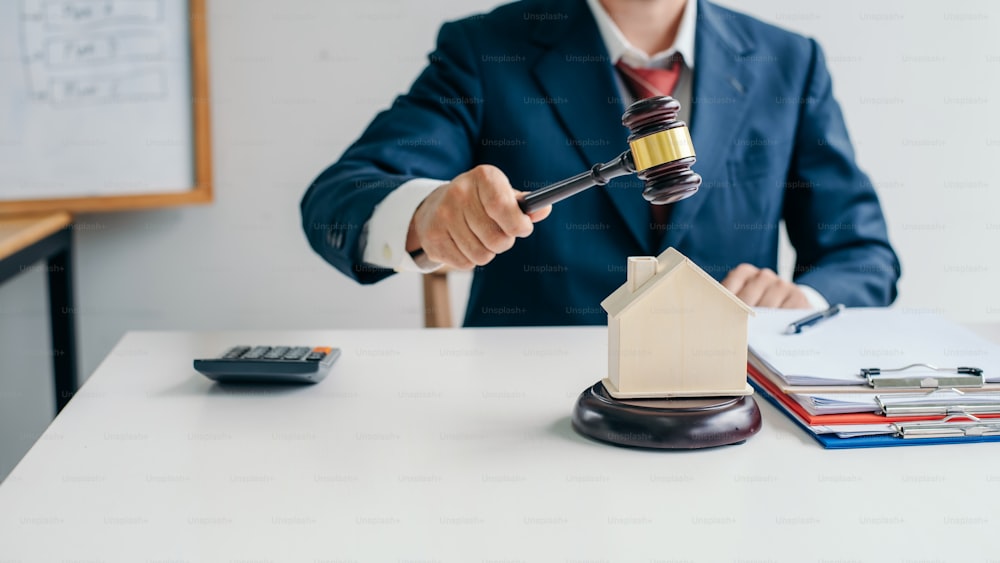 Imagem de advogado segurando um martelo de leilão em casa modelo. Conceito da lei é comprar ou vender casas e terras, hipoteca.