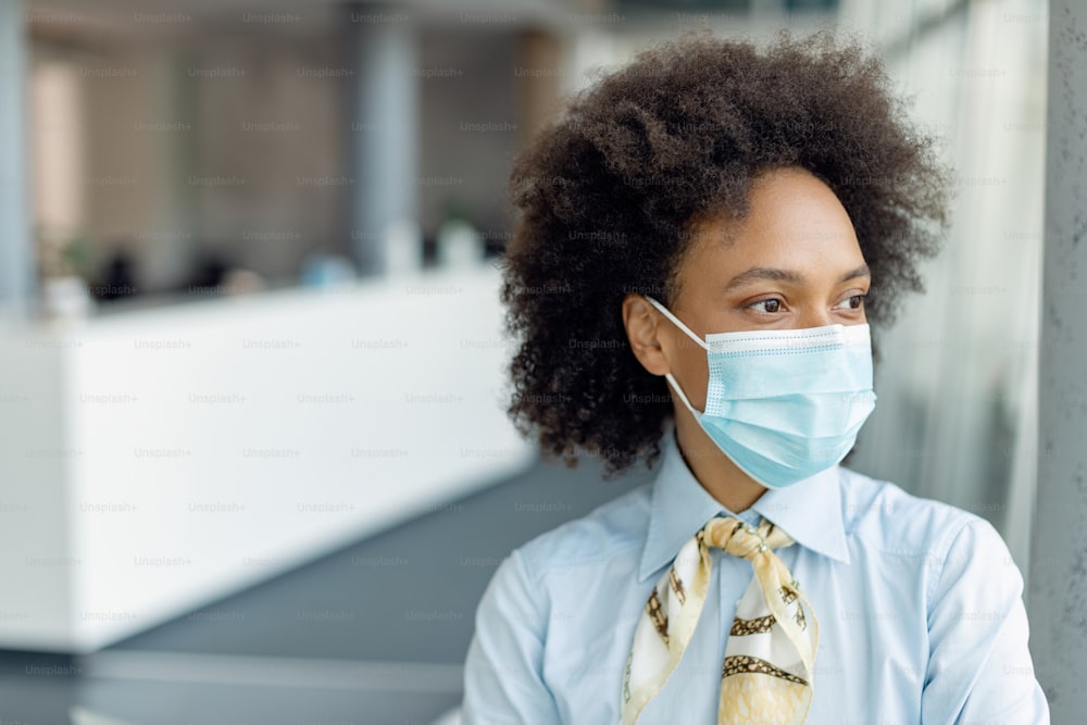 African American businesswoman wearing face mask and contemplating while standing in the office.
