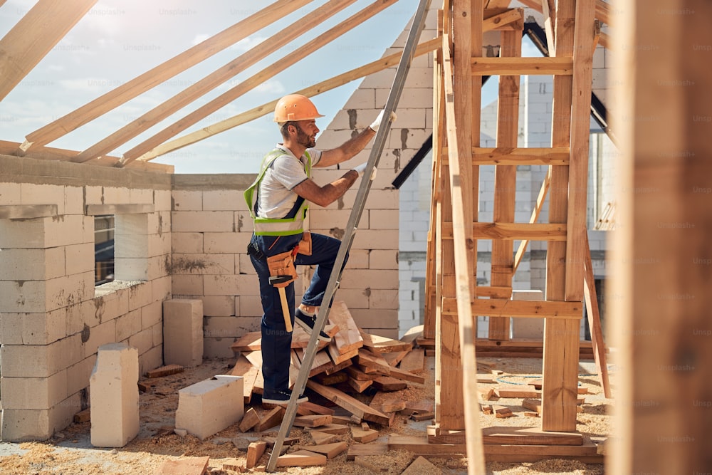 Cheerful man climbing the stairs while going to check readiness to cover the roof