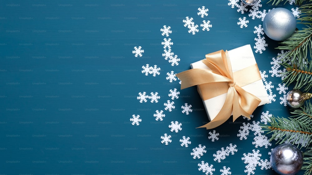 Caixa de presente de Natal, ramos de abeto, decoração de bolas, confetes de flocos de neve no fundo azul escuro com espaço de cópia. Modelo de cartão de Natal, maquete de banner de Ano Novo.