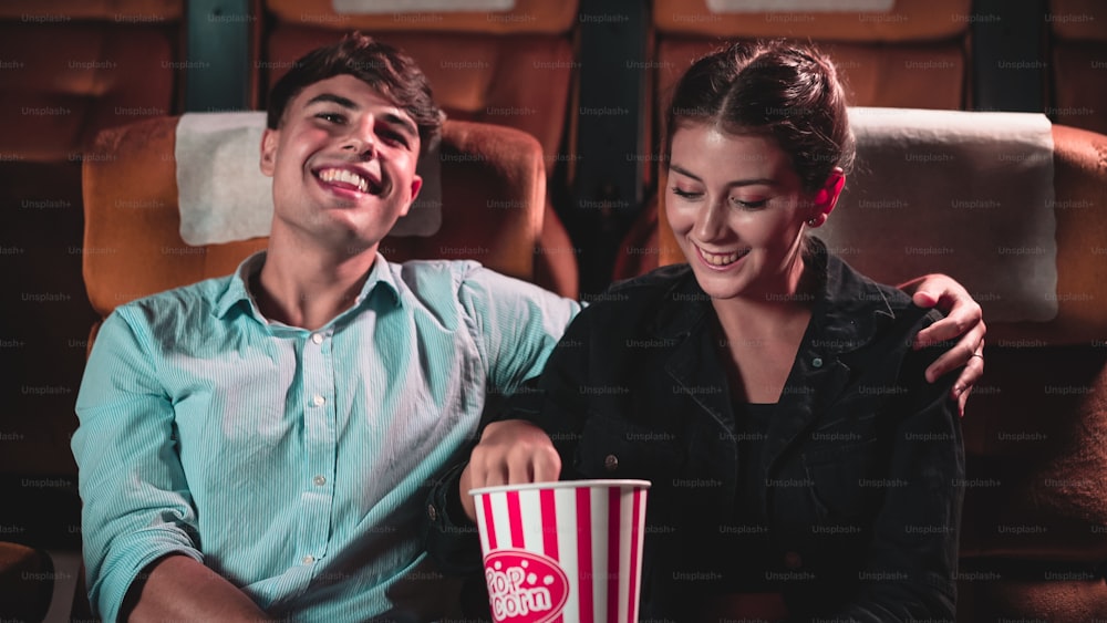 Uomini e donne stanno mangiando e lanciando popcorn è stato divertente nelle loro bocche in teatro