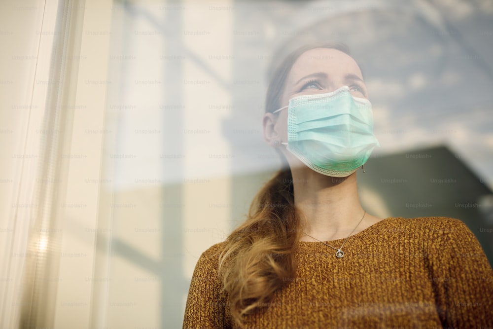 Low angle view of a woman wearing protective face mask and looking through the window. Copy space.