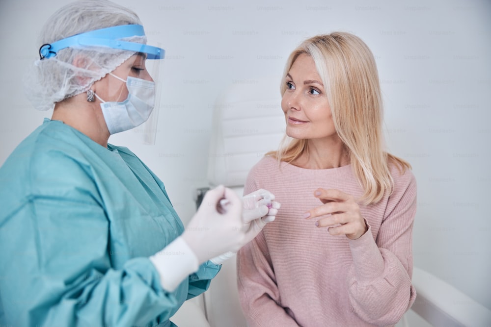 Beautiful smiling Caucasian lady looking at the virologist placing her swab into a sterile tube