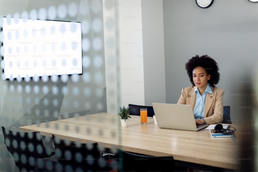 Smiling black businesswoman using laptop while working in the office.