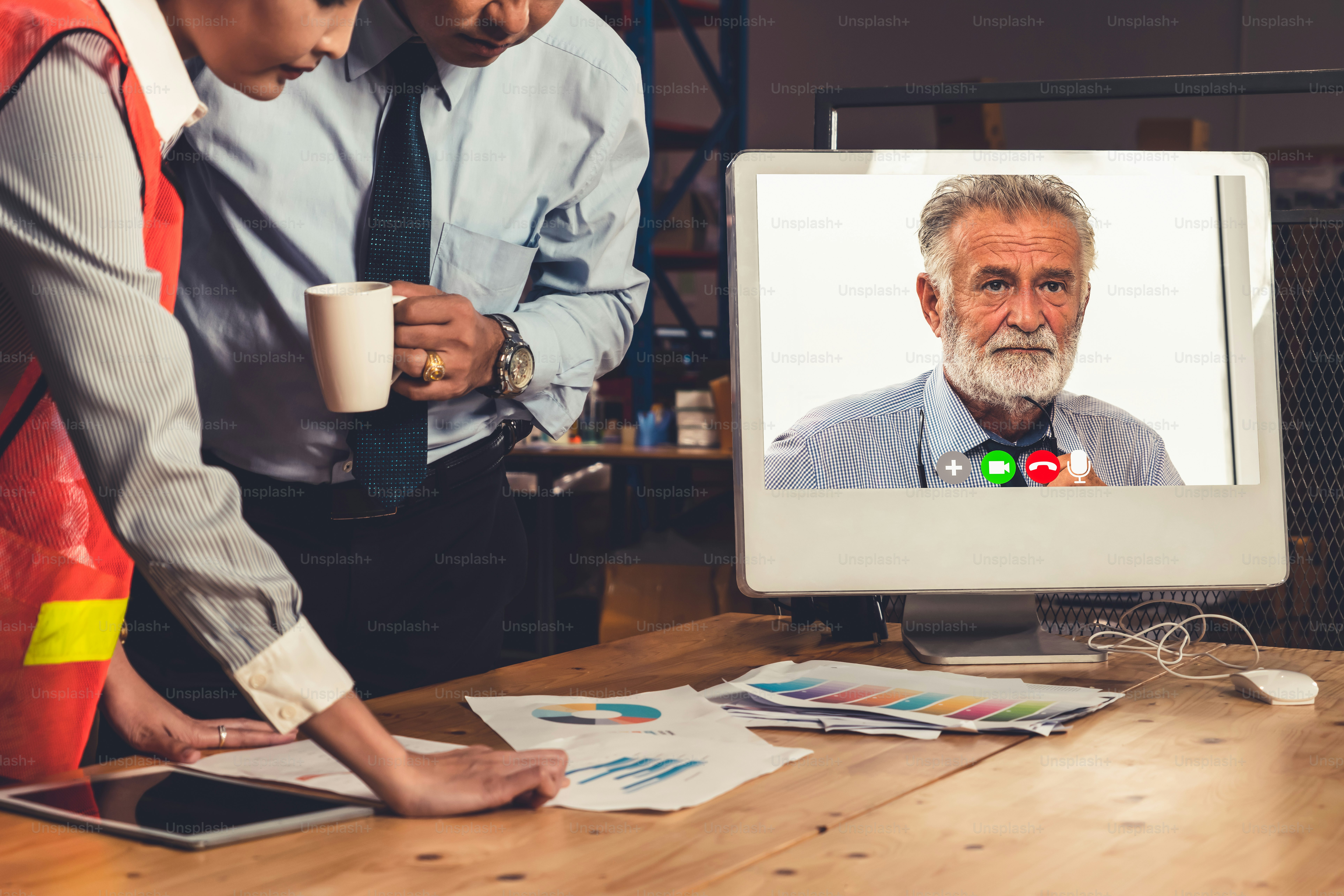 Warehouse staff talking on video call at computer screen in storage ...