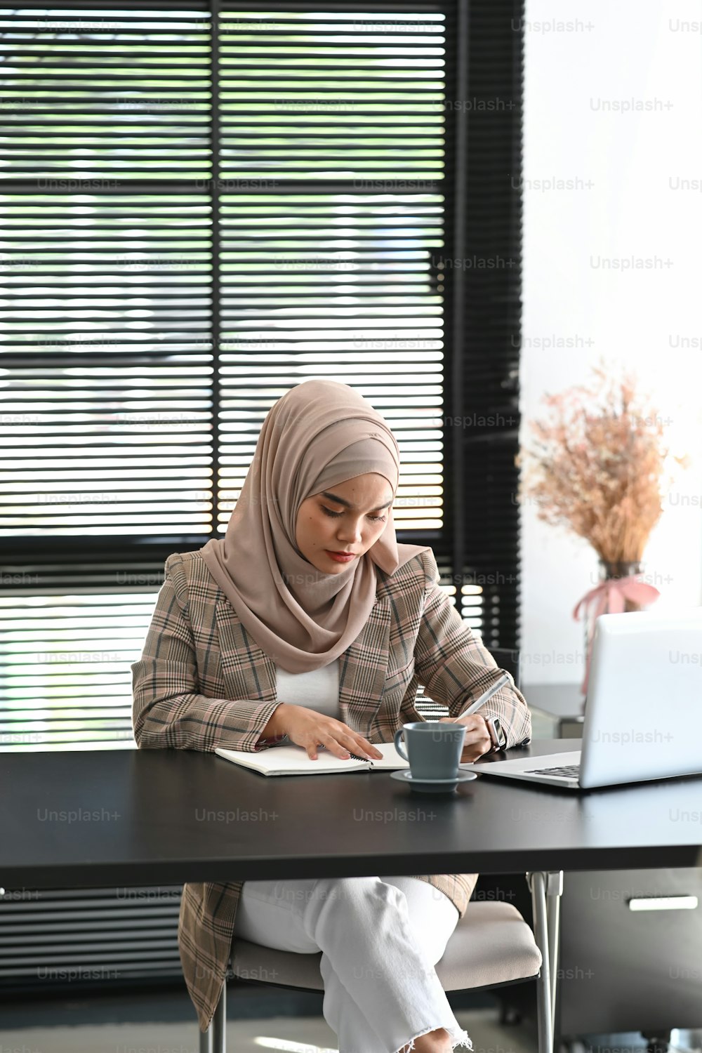 Portrait of young Arabic business woman wearing hijab in front of laptop search and doing office work.