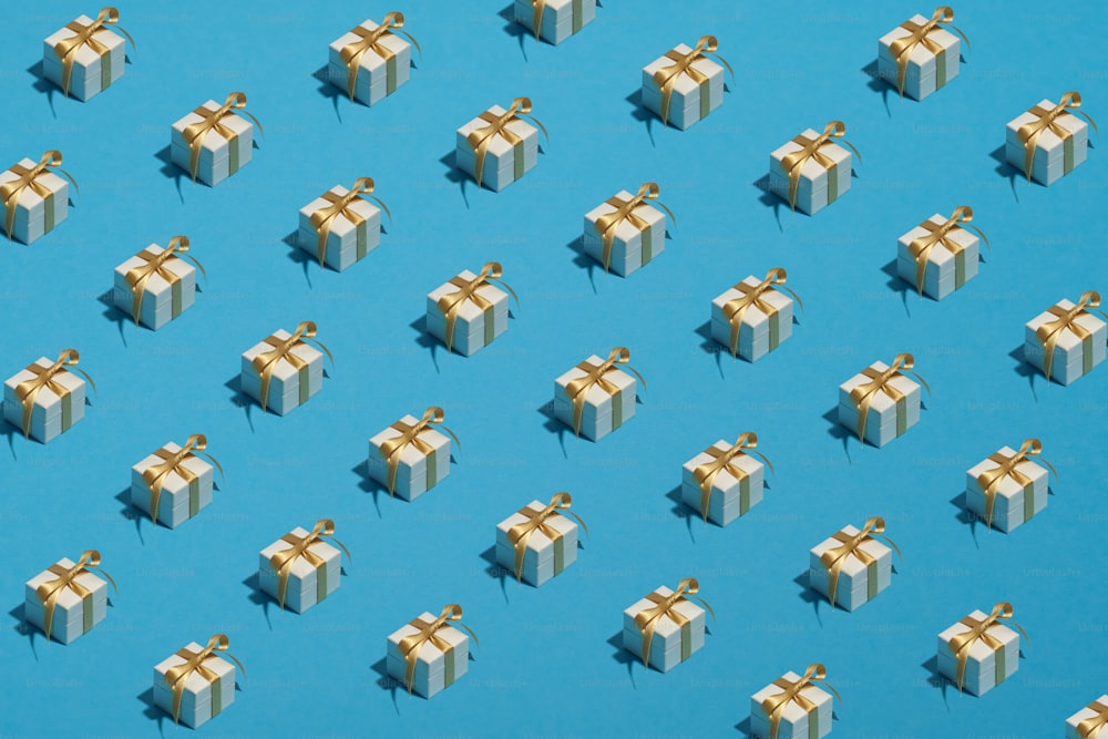 Motif de boîtes-cadeaux blanches avec noeud de ruban doré sur fond bleu. Cadeaux de Noël, concept de surprises d’anniversaire