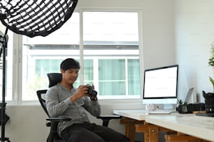 Um designer gráfico ou fotógrafo verificando a imagem na câmera enquanto está sentado em seu estúdio.