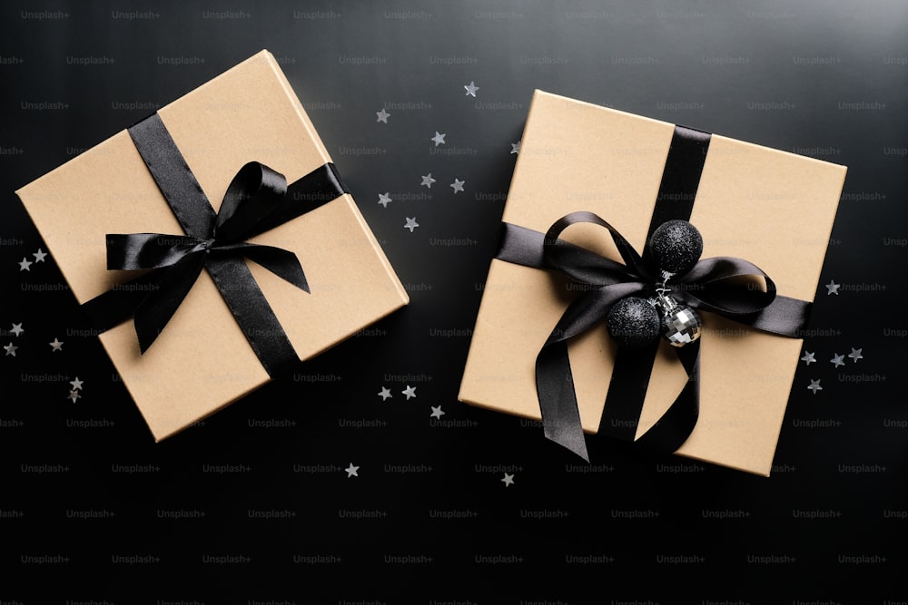 검은 배경에 리본 활과 공이 있는 고급 크리스마스 선물 상자. 플랫 레이, 평면도. 크리스마스 또는 블랙 프라이데이 판매 개념.