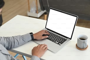 Plan recadré d’un employé de bureau travaillant avec un ordinateur portable dans son espace de travail au bureau.
