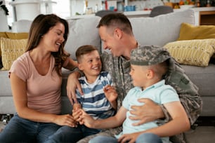 Soldado feliz sentado en el suelo con su familia. Soldado y su esposa disfrutando en casa con niños