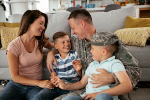 Happy soldier sitting on the floor with his family. Soldier and his wife enjoying at home with children