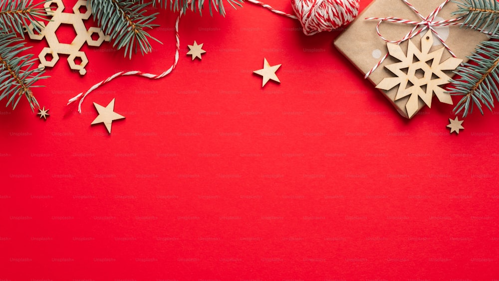 Cadre de Noël en bordure de boîte-cadeau, branches de sapin, décorations en bois, corde sur fond rouge. Maquette de bannière de Noël, modèle de conception de carte postale.