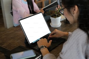 Cropped shot of an attractive businesswoman is working on computer tablet with white screen in meeting room.