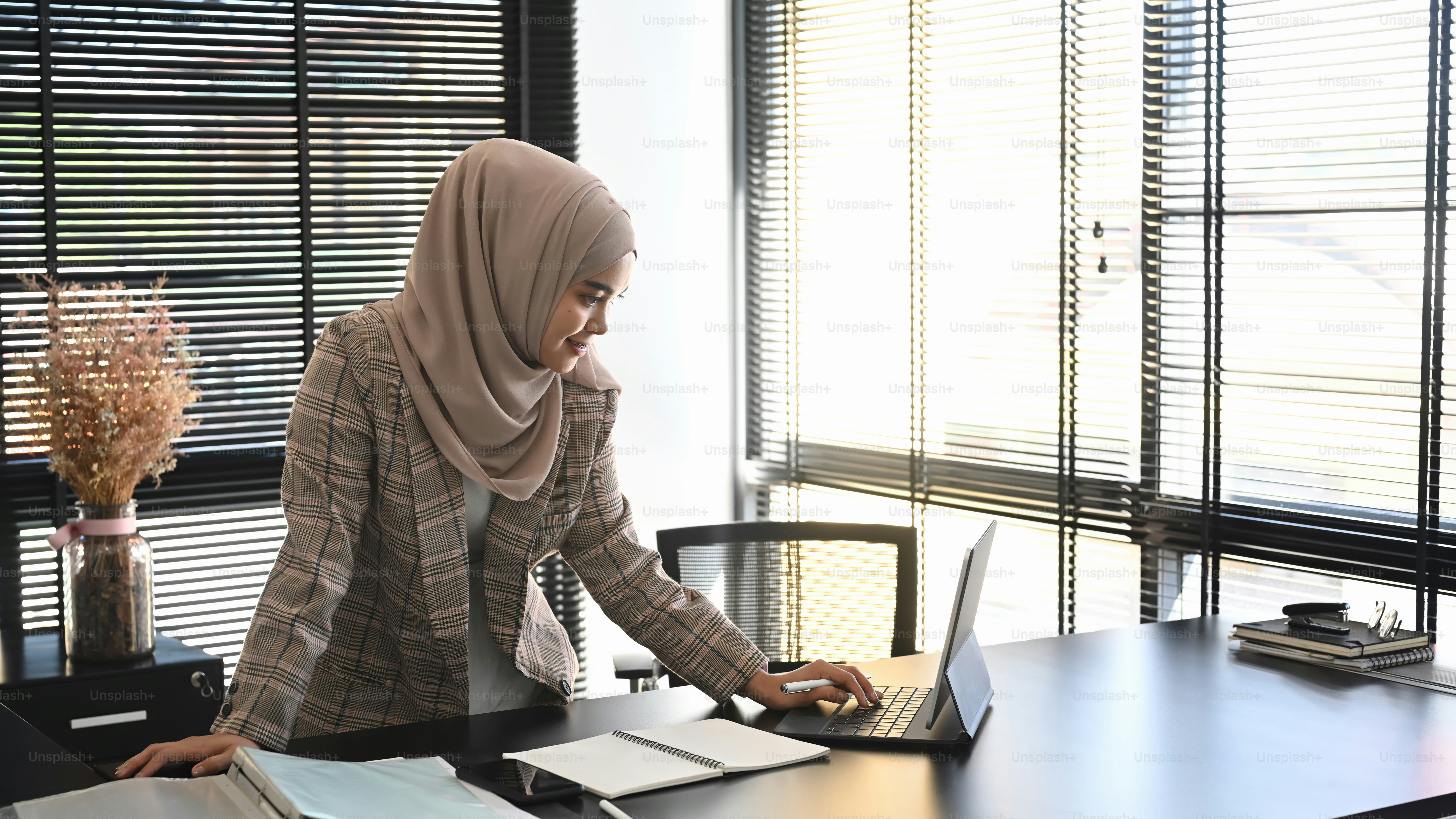 A muslim woman in headscarf is working on her project with computer ...