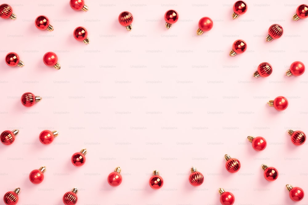 Decoração vermelha das bolas do Natal no fundo rosa pastel. Banner de Natal, maquete de cartão de Ano Novo. Estilo minimalista.