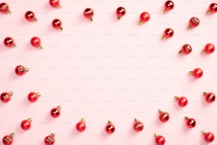 Decoración de adornos navideños rojos sobre fondo rosa pastel. Banner de Navidad, maqueta de tarjeta de felicitación de Año Nuevo. Estilo minimalista.
