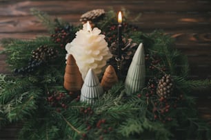 Decorazione della tavola di Natale, ghirlanda moderna fatta a mano, piccoli alberi di Natale e candele su tavolo di legno rustico. Decorazioni festive in stile per la cena delle feste a casa. Buon Natale!