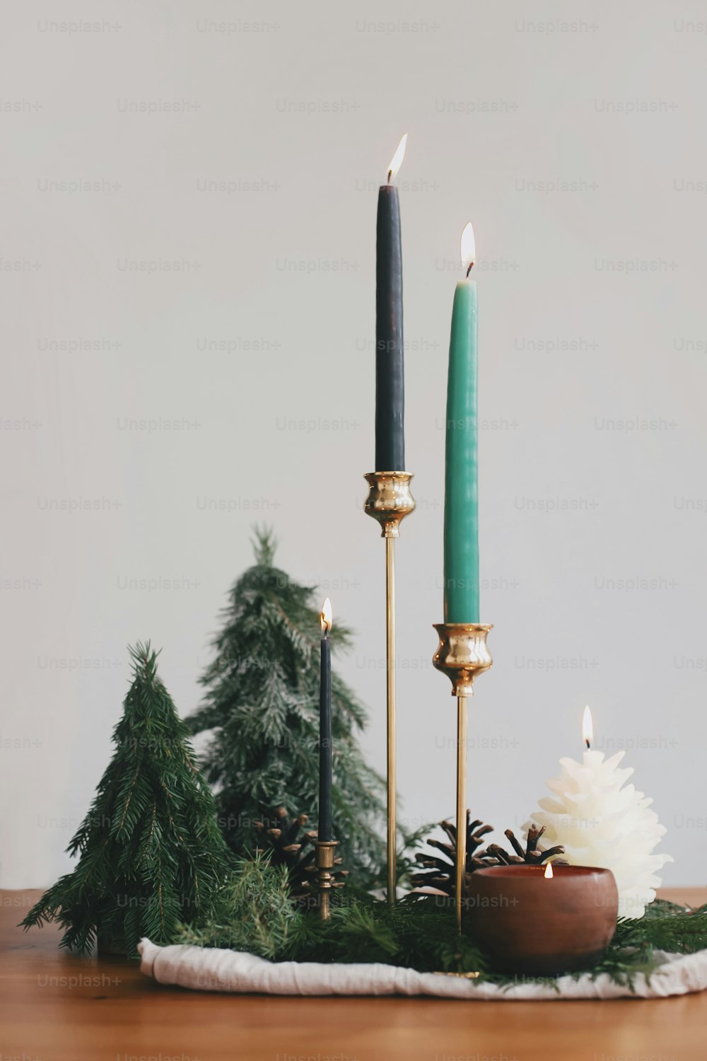 Modern Christmas table setting, stylish miniature christmas trees, candles and pine cone decorations. Festive zero waste decor and handmade little fir trees. Happy Holidays